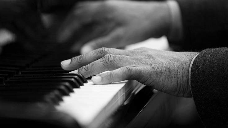 A black-and-white photo of hands playing piano keys
