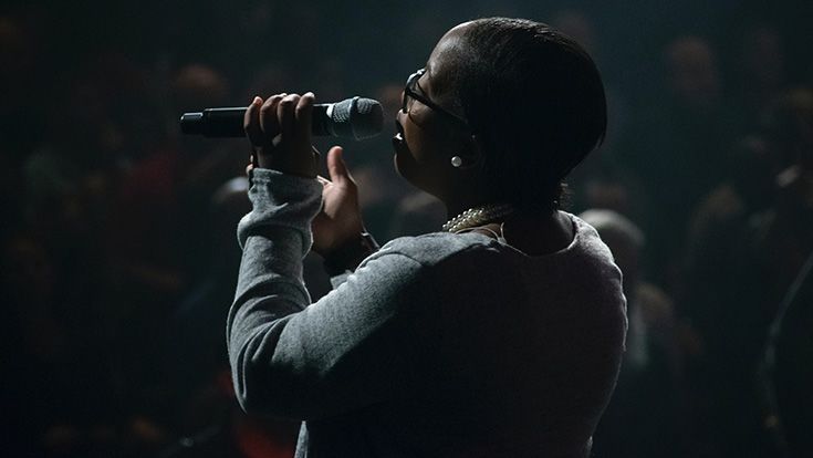 A woman holding a microphone, singing on a stage